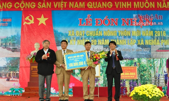 Đồng chí Vi Văn Định - Bí thư Huyện ủy Nghĩa Đàn và đồng chí Lê Hồng Sơn - Chủ tịch UBND huyện Nghĩa Đàn tặng hoa chúc mừng trao phần thưởng về đích NTM 100 triệu đồng cho xã Nghĩa Phú 