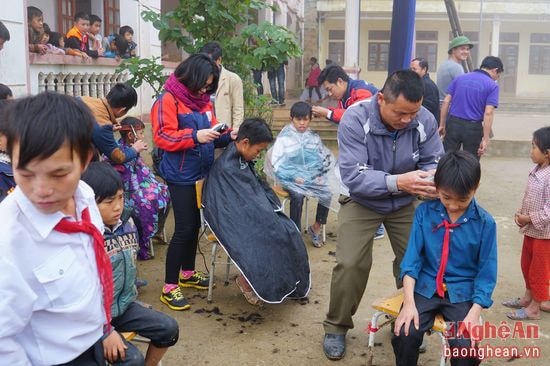 Các thành viên đoàn thiện nguyện cắt tóc cho các em học sinh