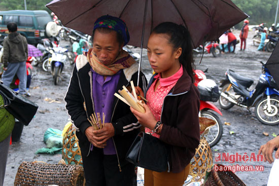 2 mẹ con người Lào che ô ăn cơm lam tại chợ để buôn bán.