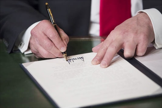 Ông Donald Trump ký vào quyết định bổ nhiệm chính mình ở Capitol, Washington ngày 20/1/2017. Ảnh: AFP