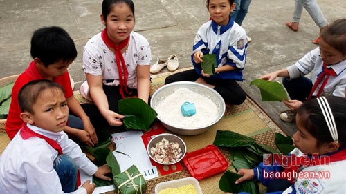 Lần đầu tiên học sinh lớp 5 được làm quen với hoạt động gói bánh chung. Ảnh Huy Thư