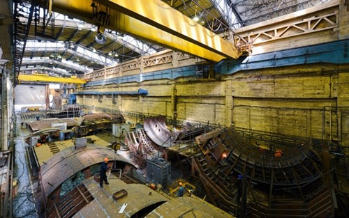 Các bộ phận như vỏ tàu ngầm và hệ thống bên trong được lắp đặt trong khu nhà xưởng rộng lớn.
