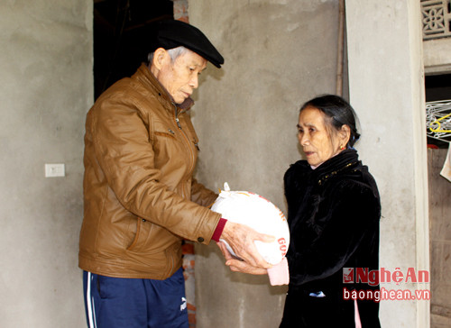 Cựu chiến binh Nguyễn Văn Thân trao gạo cho gia đình cụ Nguyễn Thị Tỵ dịp Tết Đinh Dậu. Ảnh: Huy Thư 