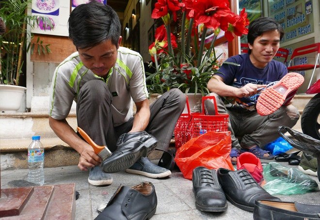 Hai anh em thợ đánh giày đang miệt mài làm đẹp cho những đôi giày diện Tết của nhiều gia đình. Ngày cuối năm, nhu cầu đánh bóng giày dép tăng vọt, họ cố gắng làm đến những giờ phút cuối cùng của năm cũ, mong kiếm thêm 