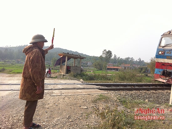 Ông Nguyễn Huy Chi giơ cờ báo hiệu an toàn khi tàu đến.