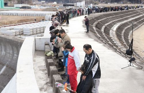 Người dân mặc niệm trên đê biển ở tỉnh Iwate. Ảnh: Reuters