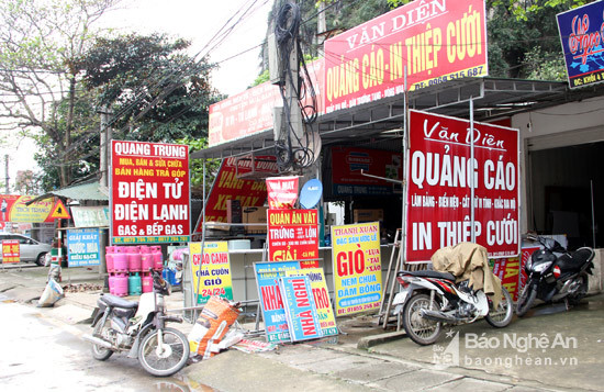 Các biển quảng cáo, hàng hóa chất đầy hành lang giao thông gần phía đối diện Chợ Con cuông, chợ lớn nhất huyện miền núi này.