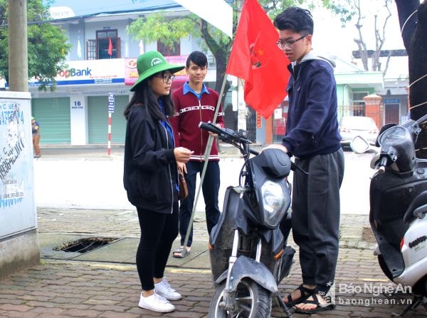 Thanh niên TP. Vinh nhắc nhở người dân chấp hành Luật Giao thông.