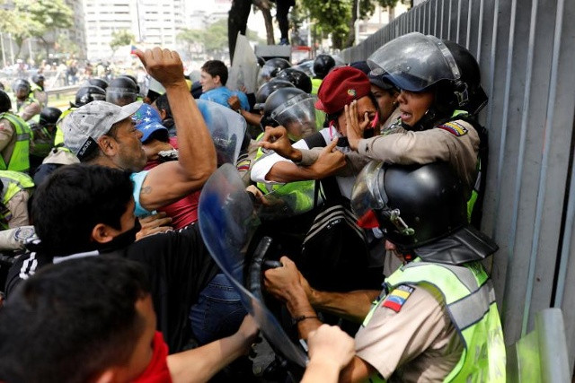 Những người biểu tình cãi nhau với lực lượng an ninh trong một cuộc mít tinh phản đối ở Caracas, Venezuela. 
