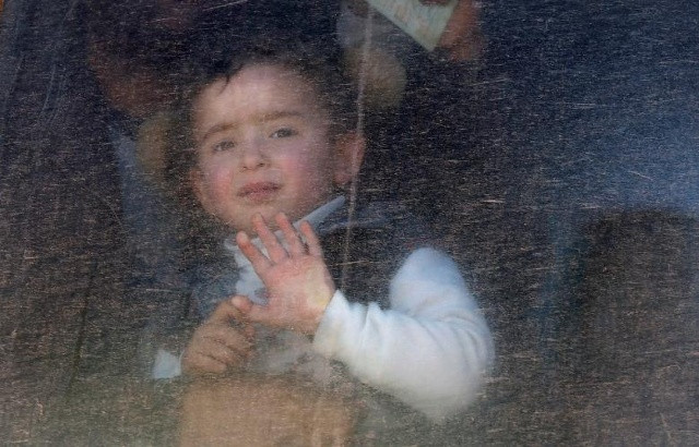Một cậu bé người Iraq đã rời khỏi nhà cùng gia đình nhìn ra cửa sổ xe buýt sau khi đến trại Al-Alil ở phía nam Mosul, Iraq