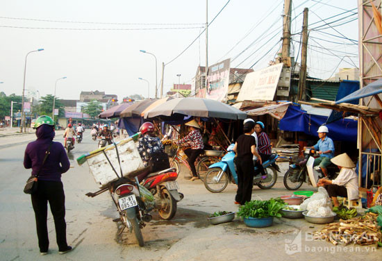 Trước một chợ chiều, các hộ buôn bán trưng hàng trên lề đường, căng dù ra giữa lòng đường. Ảnh: Huy Thư