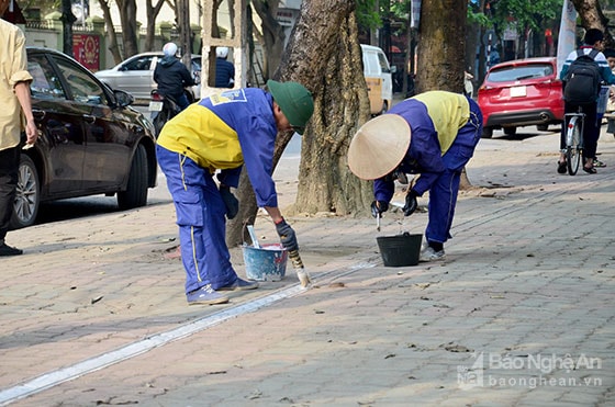 Công nhân Công ty Quản lý đô thị Vinh kẻ vẽ ranh giới đỗ xe.