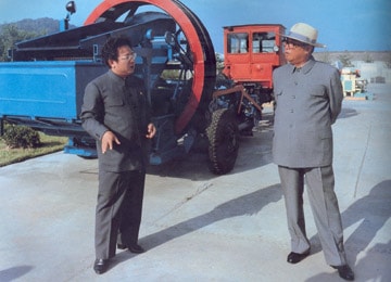 Chủ tịch Kim Nhật Thành và con trai Kim Jong Il đứng trước một cỗ máy phục vụ nông nghiệp mới xuất xưởng, tháng 8/1982. 