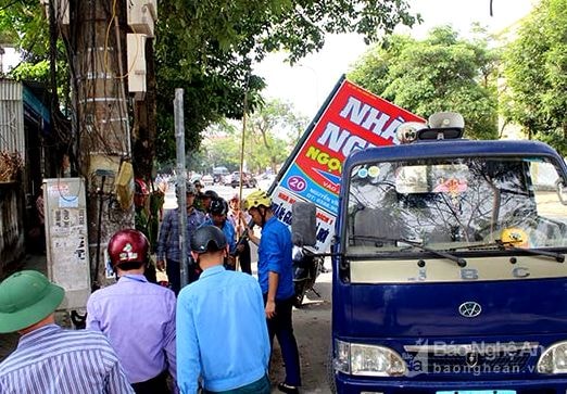 Lực lượng chức năng tháo dỡ biển quảng cáo treo sai quy định, lấn chiếm vỉa hè. Ảnh Nguyên Sơn