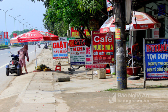 Tương tự, tại khối 2 thị trấn, nhiều biển quảng cáo đua nhau trưng bày trên vỉa hè, làm mất tầm nhìn người đi bộ. Ảnh: Quang An