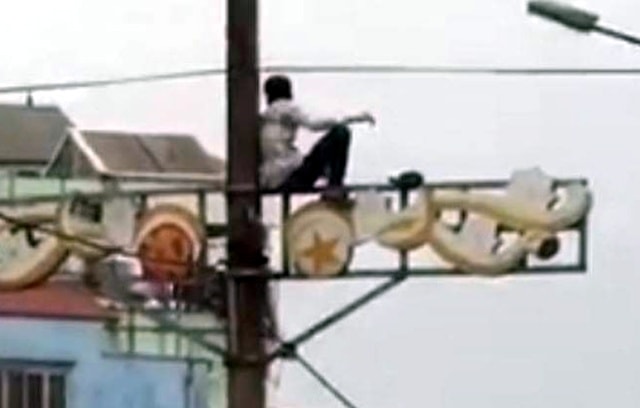Nam thanh niên ngồi trên cây cột điện.