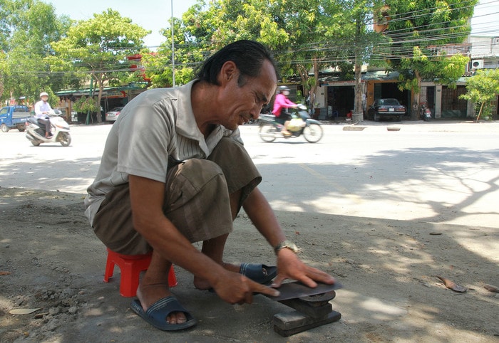 Một người mài dao vẫn cần mẫn làm việc trên hè phố đường Lệ Ninh, TP Vinh. Ảnh: Chu Thanh