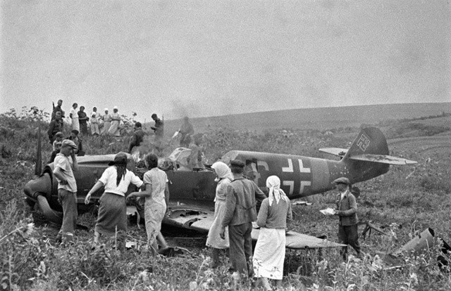 Các nông dân Liên Xô trong một hợp tác xã đang xem xét một máy bay của phát xít Đức bị bắn hạ.