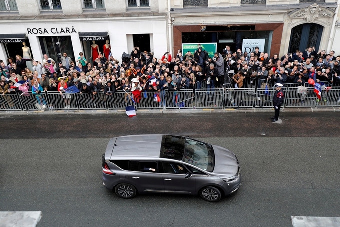 Người dân đứng bên đường dõi theo chiếc xe chở tân Tổng thống Pháp. Nhiều người vẫy cờ Pháp và cờ Liên minh châu Âu (EU) khi xe đi qua.