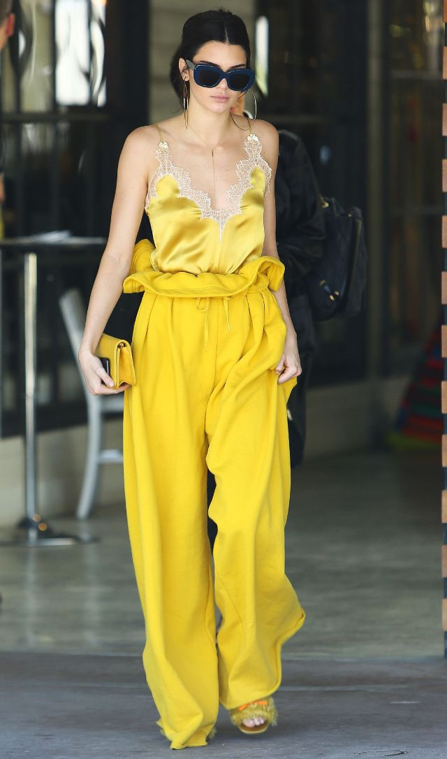 Kendall Jenner thu hút với bộ đồ màu vàng nổi bật. Hai item trái ngược nhau: áo hai dây ren mỏng phối với quần cạp túm oversized tạo nên tổng thể cá tính cho người mẫu 9X.  