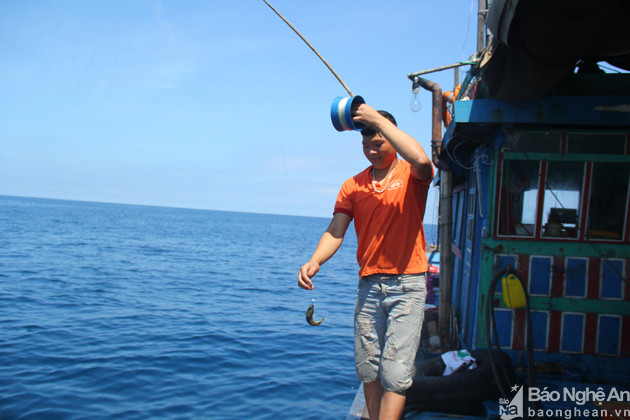 Tranh thủ những phút nghỉ ngơi, Hoàng Đức Lin Đa (18 tuổi, phường Quỳnh Phương), ra mạn tàu câu cá. Ảnh. Tiến Hùng. 