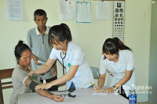 Các y bác sĩ đến từ Bệnh viện Giao thông vận tải Vinh khám, đo huyết áp cho các cụ cao tuổi xã Tà Cạ. Ảnh: Nguyễn Hải