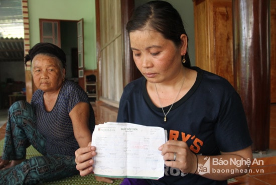 Chị Lương Thị Hiệp cùng giấy nộp tiền vào tài khoản có tên: Vũ Hoàn Vũ. Ảnh: Hồ Phương