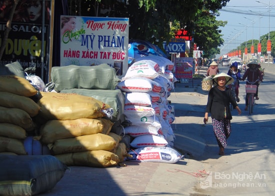 Cách đó vài nhà, một cửa hàng tạp hóa còn để chất đống từng bì hàng lấn cả vỉa hè đẩy cho người đi bộ phải xuống lòng đường