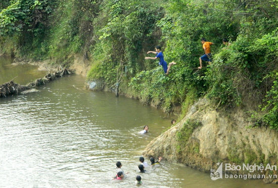 Những đứa trẻ vui đùa bằng cách leo lên mô đất cao và nhảy xuống sông Hiếu đoạn chảy qua địa bàn xã Mường Nọc, Quế Phong. Ảnh: Hùng Cường