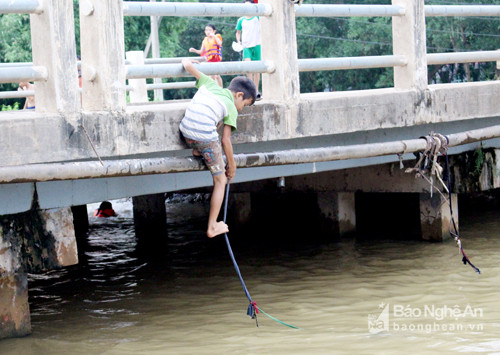 Leo trèo trên những đường ống hai bên cầu, chỉ cần sa sẩy là gặp nạn. Ảnh: Huy Thư