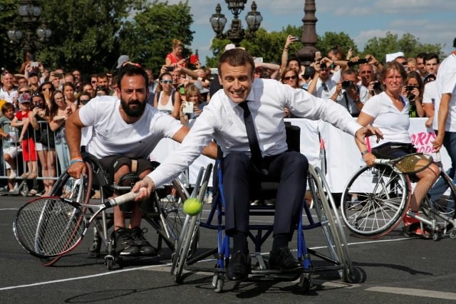 Tổng thống Pháp Emmanuel Macron trả lại quả bóng trong khi ngồi trên xe lăn khi ông chơi quần vợt trên chiếc Pont Alexandre III tại Paris, Pháp, ngày 24 tháng 6 năm 2017