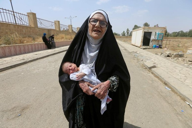 Một phụ nữ cao tuổi đã di cư ở Iraq, đã bỏ chạy khỏi các chiến binh Hồi giáo, mang một em bé ở Mosul, Iraq vào ngày 3 tháng 7 năm 2017