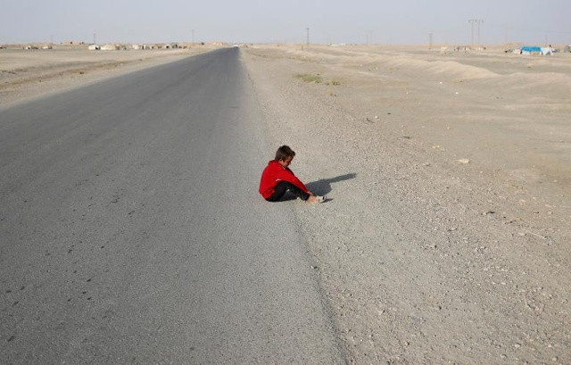Một cậu bé, đã rời khỏi chiến trường trong khu bảo tồn của Nhà nước Hồi giáo Raqqa, nằm trên một con đường gần làng Karama, phía đông Raqqa, Syria ngày 1 tháng 7 năm 2017.