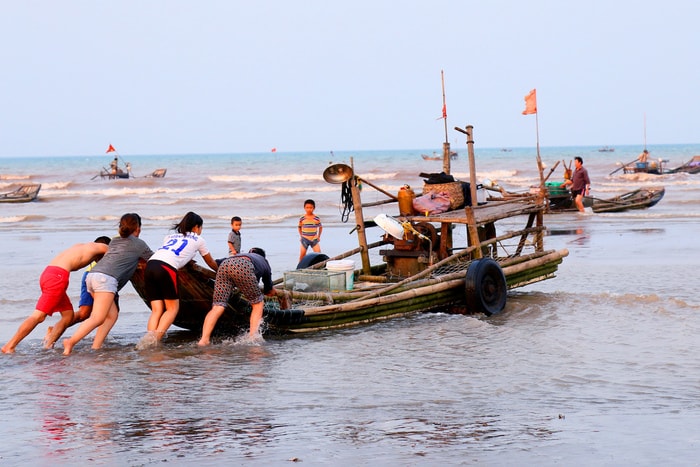 Những chiếc bè mảng được đặt lên một cặp bánh xe rồi dùng sức người vừa kéo vừa đẩy, hoặc dùng xe máy kéo khi nước ròng khơi. Ảnh: Trần Cảnh Yên