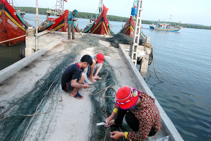 Những ngày biển động, các em lại phụ giúp cha mẹ vá lưới chuẩn bị cho chuyến đi biển mới. Ảnh: Trần Cảnh Yên