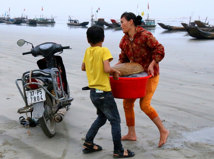 Những ngày biển động, các em lại phụ giúp cha mẹ vá lưới chuẩn bị cho chuyến đi biển mới. Ảnh: Trần Cảnh Yên