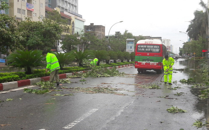 Lực lượng Cảnh sát giao thông Công an TP Vinh dọn dẹp các cành cây nằm trên đường Quang Trung để người dân và các phương tiện tham gia giao thông được an toàn. Ảnh: Phạm Bằng