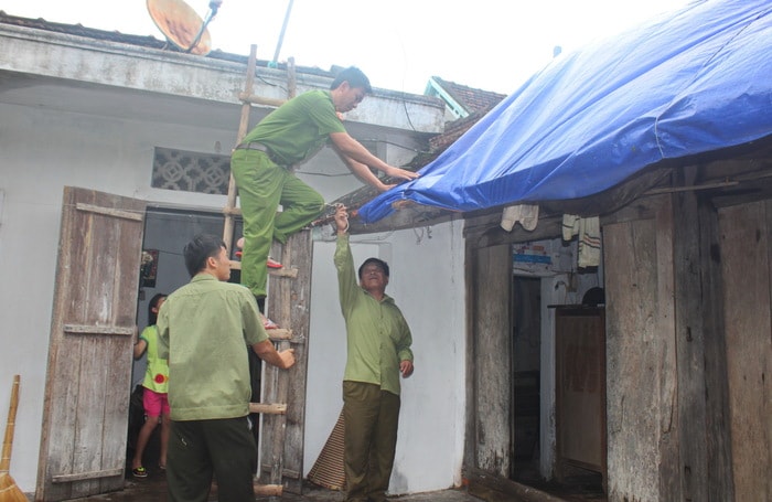 Công an huyện Quỳnh Lưu giúp người dân chằng lại mái nhà. Ảnh: Mạnh Cường