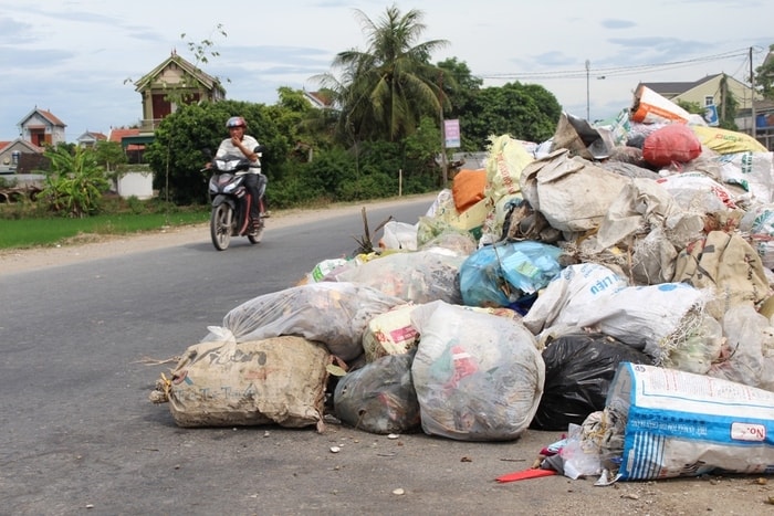 Lòng đường bị thu hẹp do rác lấn chiếm gây khó khăn cho người tham gia giao thông. Ảnh: Việt Hùng