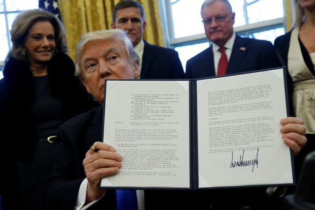 Tổng thống Trump ký sắc lệnh hành pháp dưới sự chứng kiến của các trợ lý tại Phòng Bầu Dục ngày 28 tháng 1 năm 2017. Ảnh: Reuters