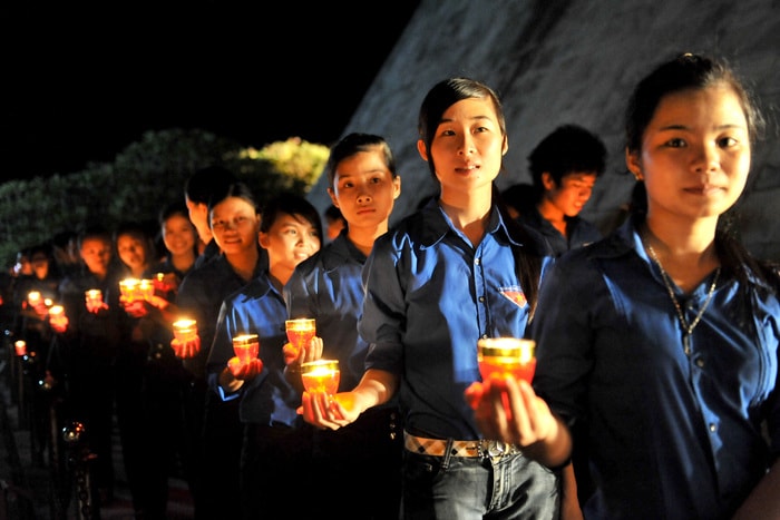 Thanh niên tình nguyện thắp nến tri ân các anh hùng liệt sỹ tại Nghĩa trang Việt - Lào (Anh Sơn).  Ảnh: Thành CHung