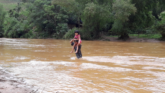 Ông Vi Văn Thái đưa các cháu sang sông tránh lụt. Ảnh: Phan Giang