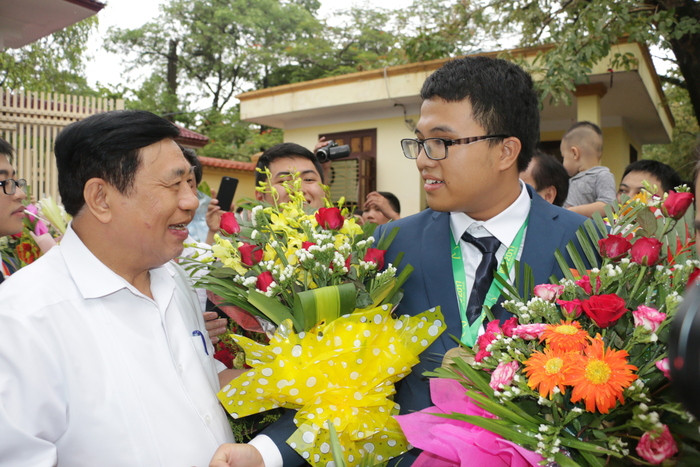 Đồng chí Nguyễn Xuân Đường tặng hoa cho em Nguyễn Cảnh Hoàng - học sinh đầu tiên đem Huy chương Vàng Olympic Toán học Quốc tế cho Trường THPT chuyên Phan Bội Châu. Ảnh: Mỹ Hà