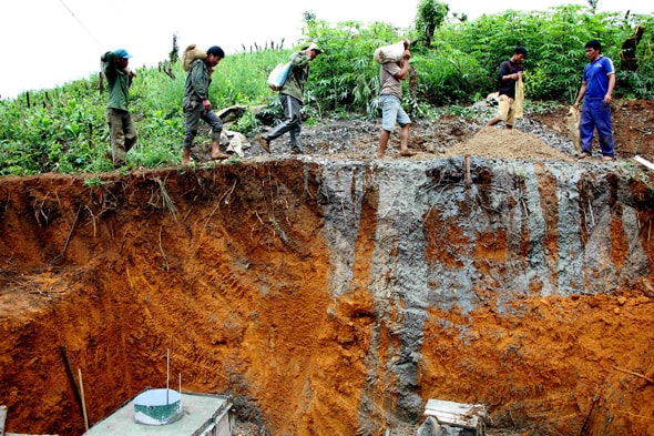 Công nhân phải cõng vật liệu xây dựng lên đồi cao để đổ lại chân trụ cột điện. Ảnh: Hùng Cường