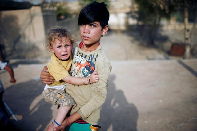 Một cậu bé Yazidi giữ em gái của mình trong một sân chơi ở khu vực Sinjar, Iraq ngày 2 tháng 8 năm 2017