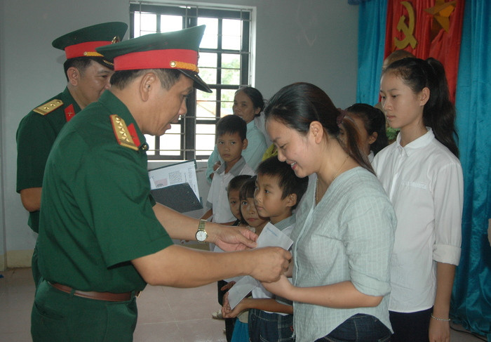 Đại tá Trần Khắc Bang - Phó Tham mưu trưởng Quân khu 4 tặng quà cho đại diện các cháu học sinh xã Hưng Trung. Ảnh: Hồ Việt