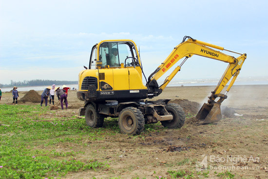 Điều động máy múc đến bãi biển đào hố để chôn lấp rác tại chỗ. Ảnh: X.Hoàng