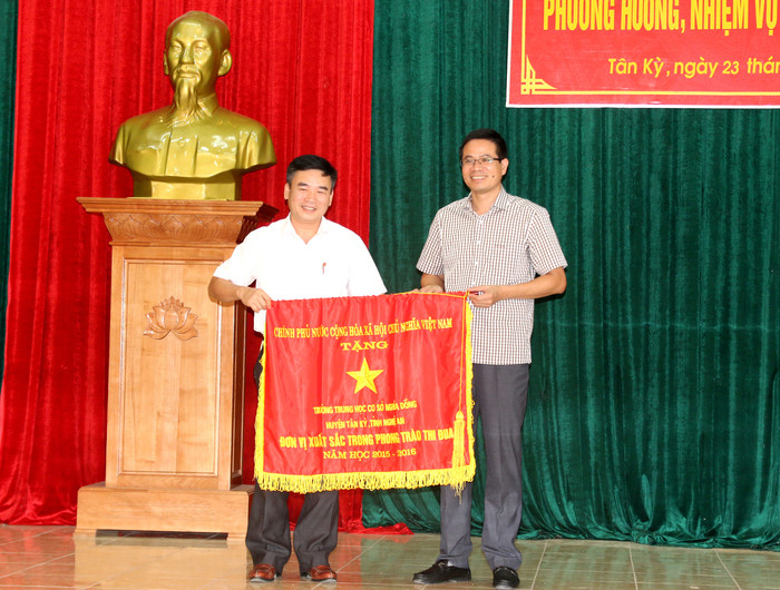 Đồng chí Đàm Hữu Hồng - Phó Bí thư Huyện ủy Tân Kỳ trao cờ thi đua của Chính phủ cho Trường THCS Nghĩa Đồng. Ảnh: Cẩm Tú