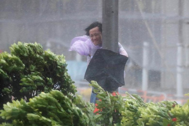 Một người đàn ông giữ một đèn chống lại cơn gió mạnh khi Typhoon Hato tấn công Hong Kong, Trung Quốc vào ngày 23 tháng 8 năm 2017