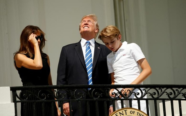 Nếu không có kính bảo vệ, Tổng thống Hoa Kỳ Donald Trump nhìn về phía nguyệt thực trong khi xem với vợ ông Melania và con trai Barron tại Nhà Trắng ở Washington, ngày 21 tháng 8 năm 2017
